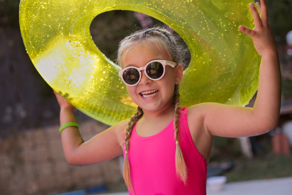 Niña con lentes de sol y un inflable para la piscina